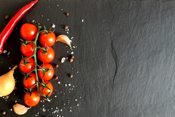 Vegetables and salt lie on a black stone background.	
