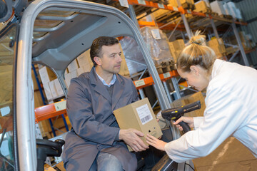 female worker scanning box held by forklift driver