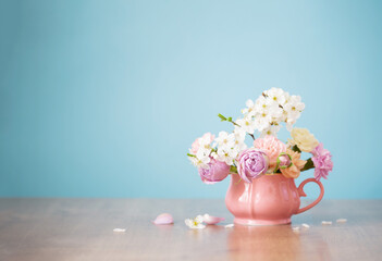 beautiful spring flowers in vintage cup in pastel colors on blue background