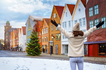 A happy tourist woman looks at the Christmas deocrated Bryggen district in Bergen, Norway, during a...