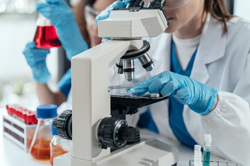 Team of biochemical research scientists working with a microscope for vaccine development.