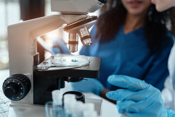 Team of biochemical research scientists working with a microscope for vaccine development.