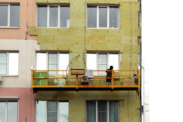 A worker covers the wall of a building with insulation.