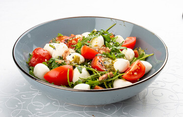 Caprese salad, cherry tomatoes, mozzarella, arugula and pesto sauce. Isolated image