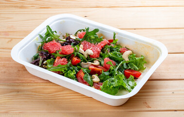 Juicy salad with grapefruit and arugula. Healthy diet. Takeaway food.  On a wooden background.