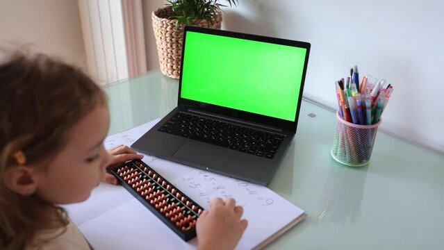 A girl from the back is engaged in mental arithmetic on the abacus online on a laptop, chroma key background. The concept of teaching children to count quickly, Russian mathematics.