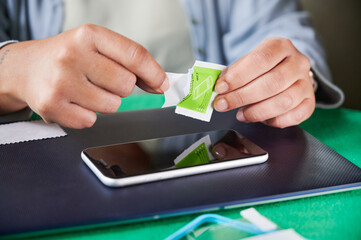 Unrecognizable woman opens a wet wipe to clean the mobile phone screen before installing a new...