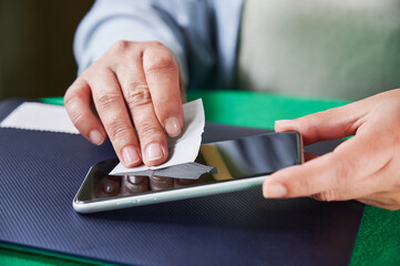 Unrecognizable woman using a wet wipe to clean the mobile phone screen before installing a new...