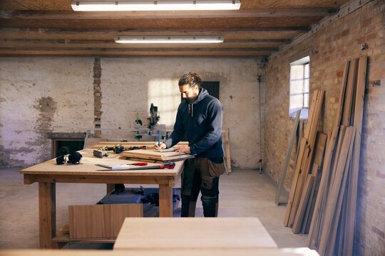 Carpenter drawing a design in his workshop