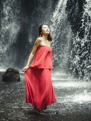 Asian woman posing near waterfall. Nature and environment. Water splashing. Travel lifestyle....