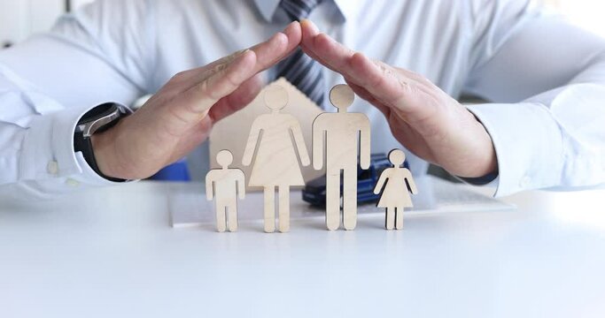Male hands over a wooden family model, close-up, slow motion. Property and health insurance