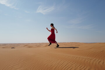 Fototapeta na wymiar Woman in red dress on sand dunes