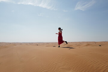 Woman in red dress on sand dunes