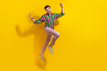Fototapeta na wymiar Full body photo of young boyfriend wearing stylish vintage old school garment raised fists up jumping isolated on yellow color background