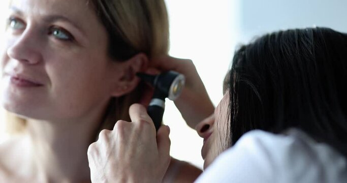 An otolaryngologist doctor looks at a woman's ear close-up. Medical tools for diagnosing a disease. Hearing loss diagnosis
