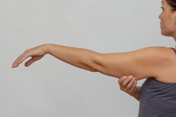 Cropped woman body showing arm with sagging skin on grey background
