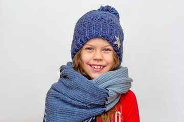 Portrait of caucasian happy smiling little girl in red with blue hat and scarf of 6 7 years old looking at camera