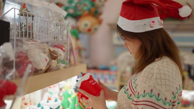 Young asian woman in santa hat choosing christmas gift for Christmas Festive. Female choosing items to decorate home for Christmas. Christmas celebration. Christmas decorated