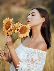 Close up portrait of attractive Caucasian woman holding sunflowers. Nature and outdoor concept. Summer time. Beautiful face profile.