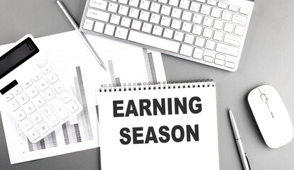 EARNINGS SEASON text on a notebook with keyboard on grey background