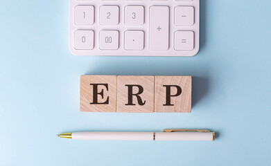 ERP on wooden cubes with pen and calculator, financial concept