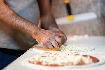 Hands preparing a pizza putting cheese mozzarella on pizza