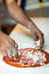 Hands preparing a pizza putting cheese mozzarella on pizza