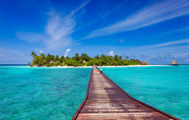 Long wooden jetty over blue ocean to tropical island beach - obrazy, fototapety, plakaty
