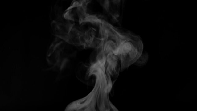 White steam from hot food or drink. White steam on a black background rises to the top. Cooking a hot meal in the kitchen.