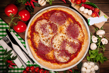 Pizza with Salami, mozzarella and tomato sauce. Pizza on a wooden table
