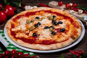 Delicious hot pizza with salmon, olives, tomatoes and spices on wooden table