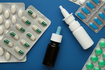Nasal spray with pills on blue background. Top view