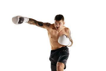 Concentrated muscular shirtless young man, boxing athlete in motion, training isolated over white background. Concept of professional sport, combat sport, martial arts, strength