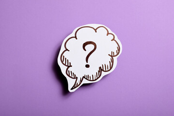 Paper speech bubble with question mark on violet background, close-up