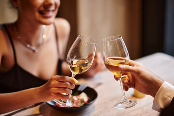 happy couple clinking glasses of white wine during date on Valentines day, romantic dinner - obrazy, fototapety, plakaty