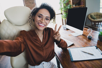 Photo of successful it specialist sit chair make selfie record video demonstrate v-sign workstation...