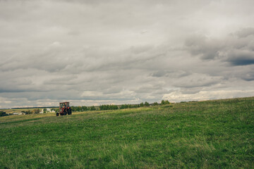 A tractor drives along a rural road along a green field. - 693008219