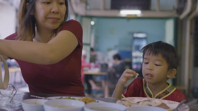 Mom with kindergarten kid boy eating chicken rice steam travel in Yaowarat China town Bangkok Thailand