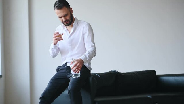 In formal clothes. Business failure. Upset young man drinker alcoholic is indoors.