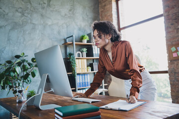 Photo of elegant successful lady use computer hold pen write clipboard document loft interior...