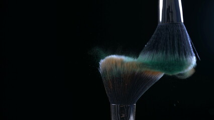 Cosmetic accessories brushing each other in super slow-motion at orange and green colors in black backdrop captured wiht high speed camera at 1000 fps