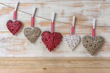 Wicker hearts made of straw hanging on brown rope on wooden background. Valentine day or love concept. Copy space.