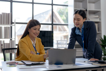 Asian businesswomen collaborate and discuss business plan during team meeting in modern office.