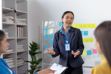 Asian businesswomen collaborate and discuss business plan during team meeting in modern office.