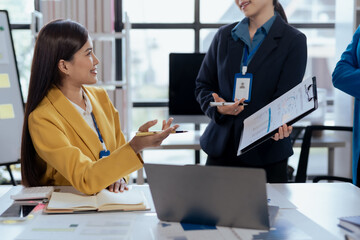 Asian businesswomen collaborate and discuss business plan during team meeting in modern office.