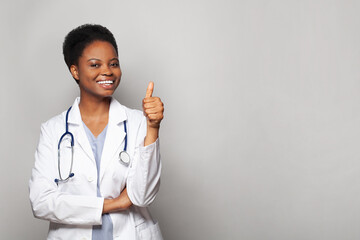 Happy doctor woman showing thumb up gesture on white background