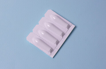 Suppository for anal or vaginal use on a blue background. Candles for treatment of hemorrhoids,...