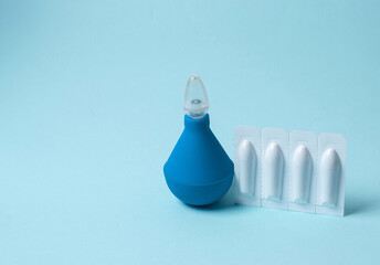 Enema and suppository for anal or vaginal use on a blue background. Candles for treatment of...