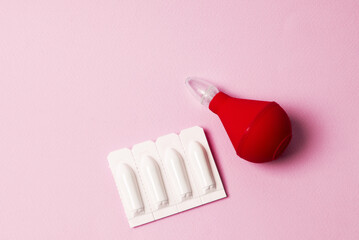 Enema and suppository for anal or vaginal use on a pink background. Candles for treatment of...
