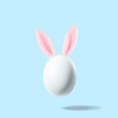 Naklejka na ściany i meble White egg with pink bunny ears against pastel blue background. Easter minimal concept. Creative Happy Easter or spring layout.